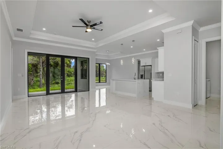 Unfurnished living room with crown molding, ceiling fan, french doors, recessed lighting, and a raised ceiling