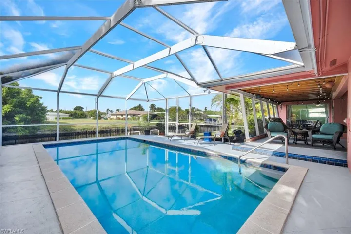 Swimming pool featuring a patio, glass enclosure, and a sunroom