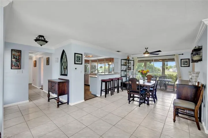 Dining space with ornamental molding, a ceiling fan, and light tile patterned flooring