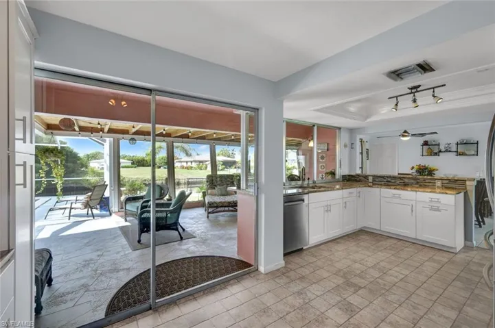 Kitchen with white cabinetry, a raised ceiling, dishwasher, dark stone counters, and ceiling fan