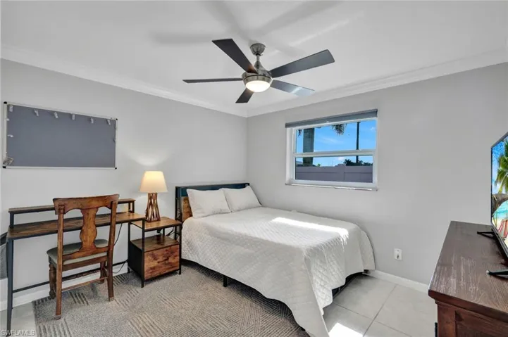 Bedroom with crown molding, ceiling fan, and light tile patterned floors