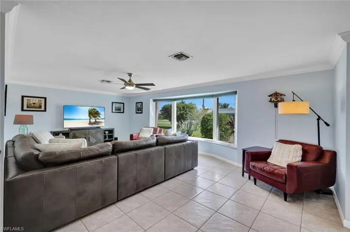 Living room featuring crown molding, a ceiling fan, and light tile patterned flooring