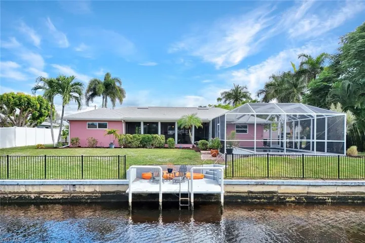 Rear view of house with a fenced backyard, a water view, a lanai, and a patio area