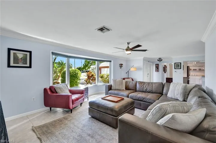 Living room featuring ornamental molding, a ceiling fan, and light tile patterned flooring