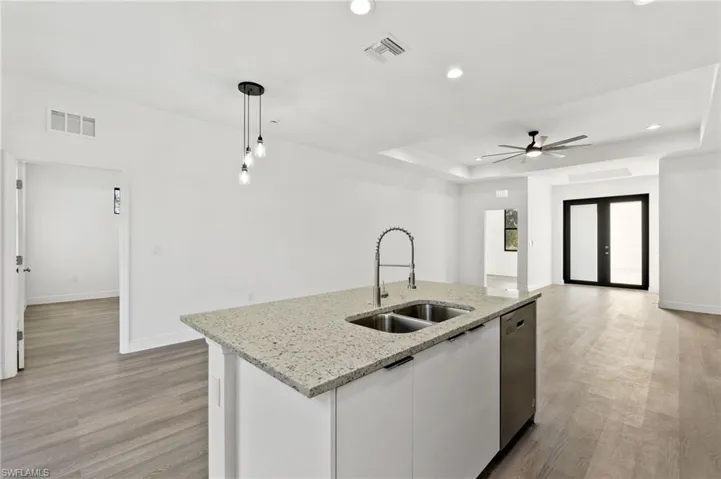 Kitchen featuring pendant lighting, sink, white cabinets, a kitchen island with sink, and stainless steel dishwasher
