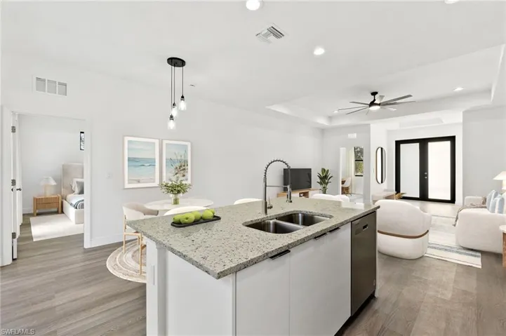 Kitchen with decorative light fixtures, sink, white cabinets, a kitchen island with sink, and stainless steel dishwasher
