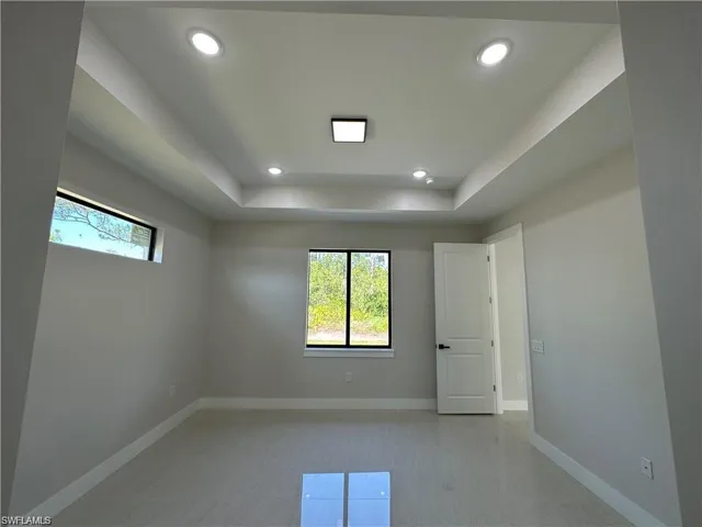 Unfurnished room with light tile patterned flooring and a tray ceiling