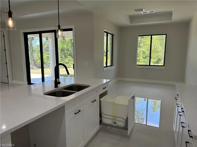 Kitchen with sink, decorative light fixtures, white cabinetry, and plenty of natural light