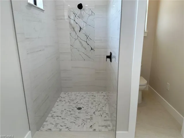 Bathroom featuring tiled shower and toilet