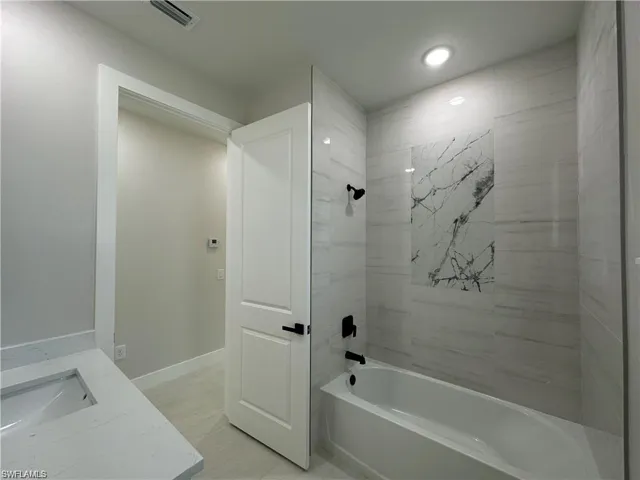 Bathroom with tiled shower / bath combo and vanity