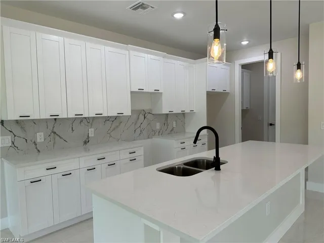 Kitchen with sink, a center island with sink, and backsplash