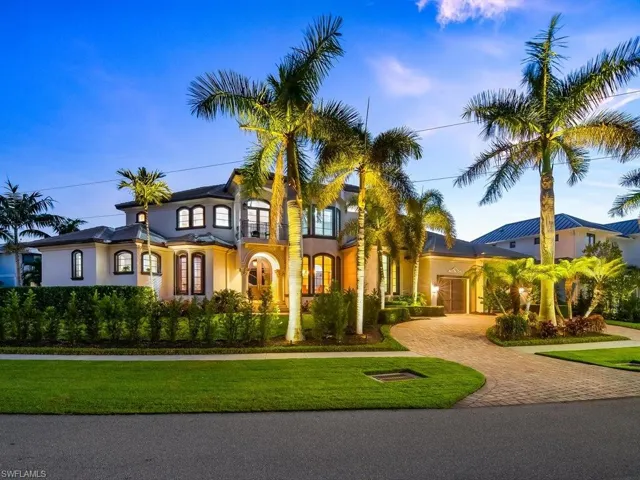 View of front of property featuring decorative driveway, stucco siding, a front yard, and a balcony