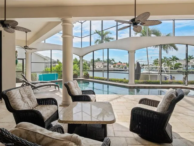 Outdoor pool featuring a sunroom, a lanai, a water view, and a patio area