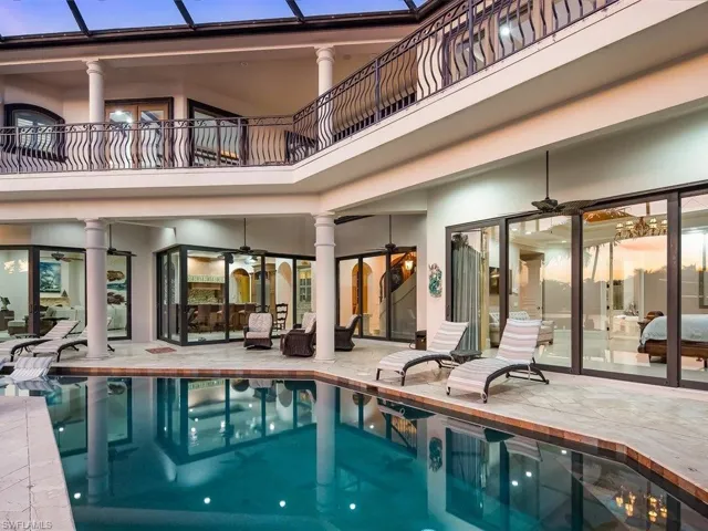 Back of house featuring a ceiling fan, an indoor pool, a balcony, and a patio