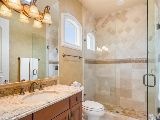 Full bathroom with vanity, a stall shower, and wallpapered walls