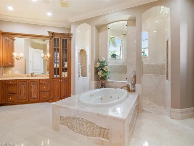Full bathroom featuring a walk in shower, vanity, ornamental molding, and a whirlpool tub