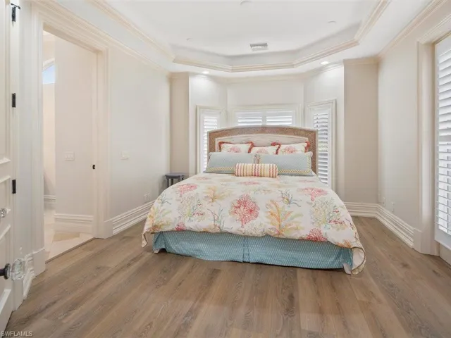Bedroom featuring a raised ceiling, light wood finished floors, crown molding, and recessed lighting