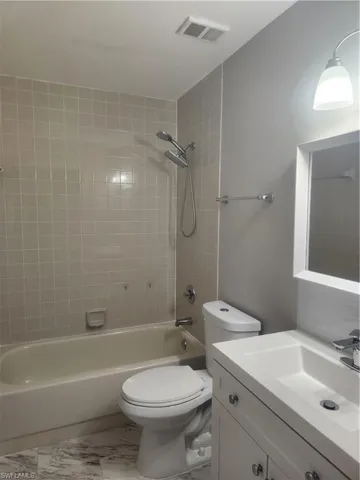 Bathroom with vanity, visible vents, shower / washtub combination, toilet, and marble finish floor
