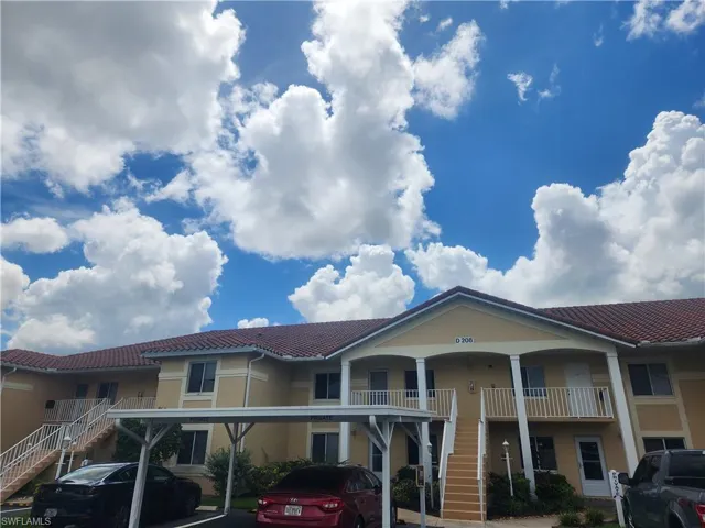 View of front of home featuring a tile roof, stairway, covered parking, and stucco siding