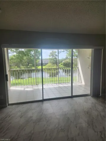 Unfurnished room featuring plenty of natural light, marble finish floor, a textured ceiling, and a water view