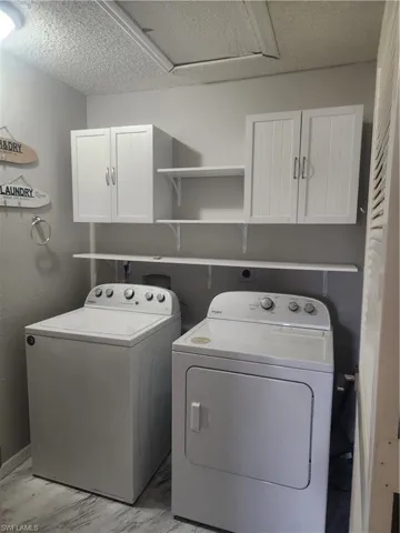Laundry area with cabinet space, washing machine and dryer, and marble finish floor