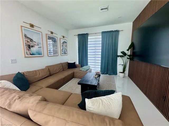 Living area featuring white walls, white tile flooring, and a full-wall wood-slat accent wall