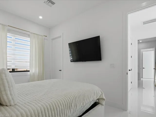 Bright room featuring a window with layered shades and sheer curtains, recessed lighting, and a wall-mounted television