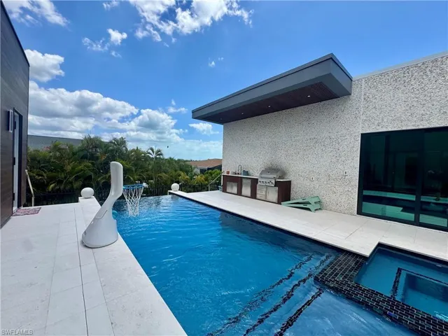 Outdoor entertainment area featuring a sparkling pool with an integrated spa