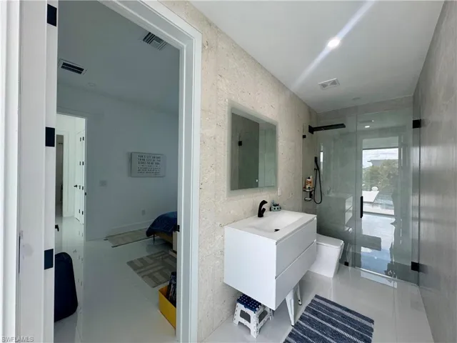 Contemporary bathroom featuring a floating white vanity with integrated sink, a frameless mirror, and a glass-enclosed shower with black hardware