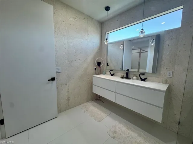 Floating double vanity with integrated sinks, black fixtures, and a large mirrored backsplash