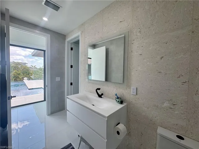 Bathroom featuring a modern floating vanity with an integrated sink, matte black faucet, and illuminated mirror