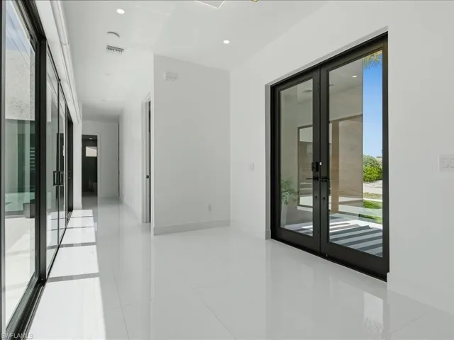 Entryway featuring dual glass panel doors, high-gloss tile flooring, recessed ceiling lighting, and a hallway with sliding glass doors