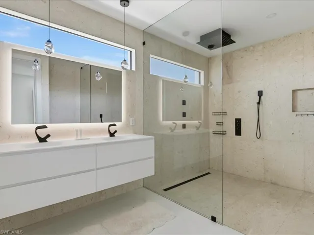 Floating double vanity with integrated sinks, back-lit mirror, and matte black fixtures