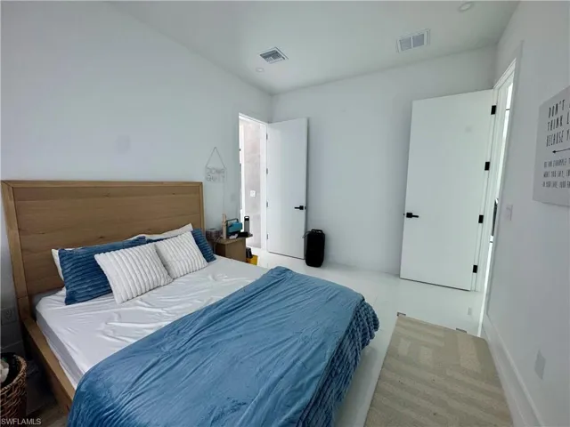 Bright interior space featuring white walls and a large light wood bed frame