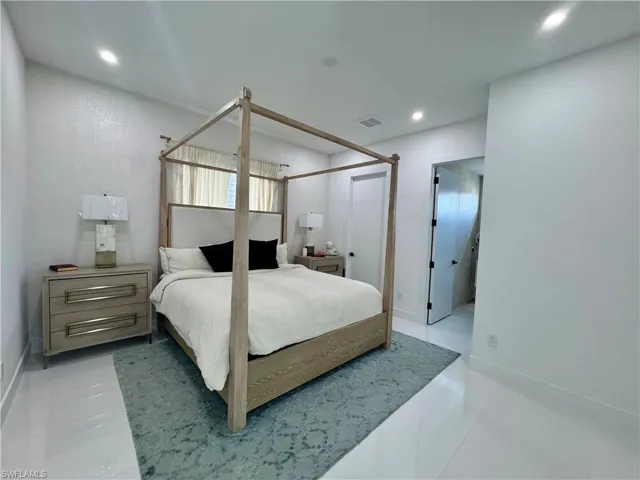 Bedroom featuring light-toned flooring, recessed ceiling lighting, and a textured accent wall