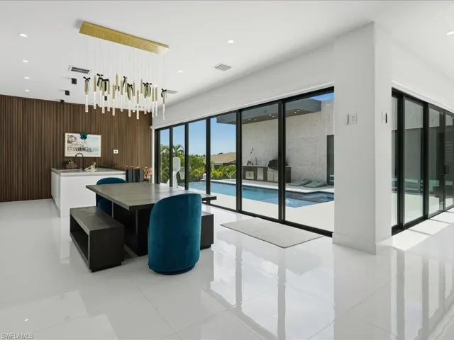 Open-concept interior featuring large format white tile flooring, a contemporary linear chandelier, and a wood-paneled accent wall