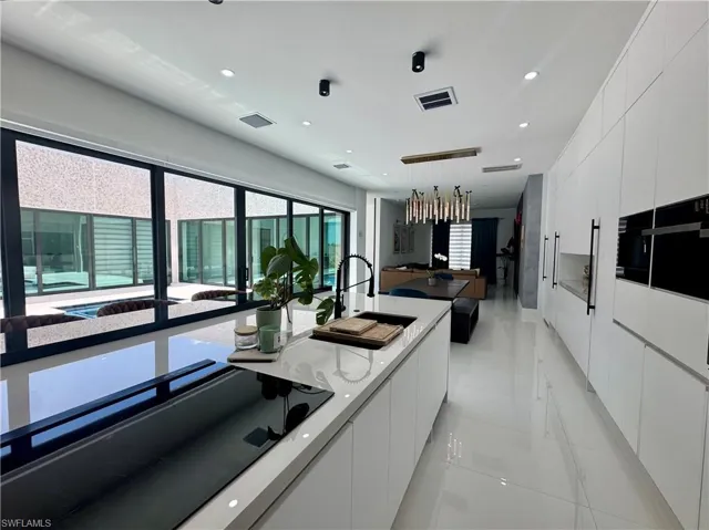 Modern kitchen featuring a white center island with an integrated cooktop and a black gooseneck faucet