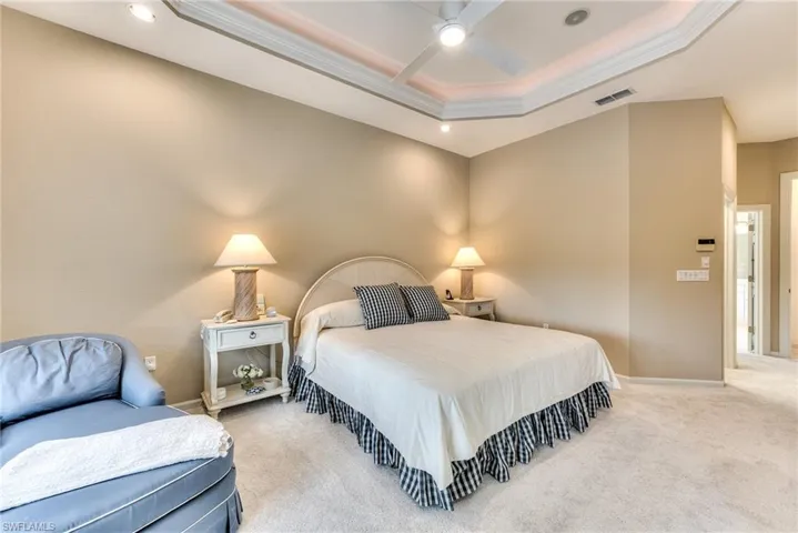 Bedroom with ceiling fan, carpet flooring, crown molding, and a raised ceiling