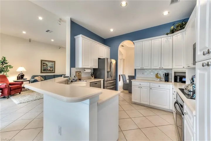 Kitchen with light tile patterned floors, white cabinetry, stainless steel appliances, and kitchen peninsula