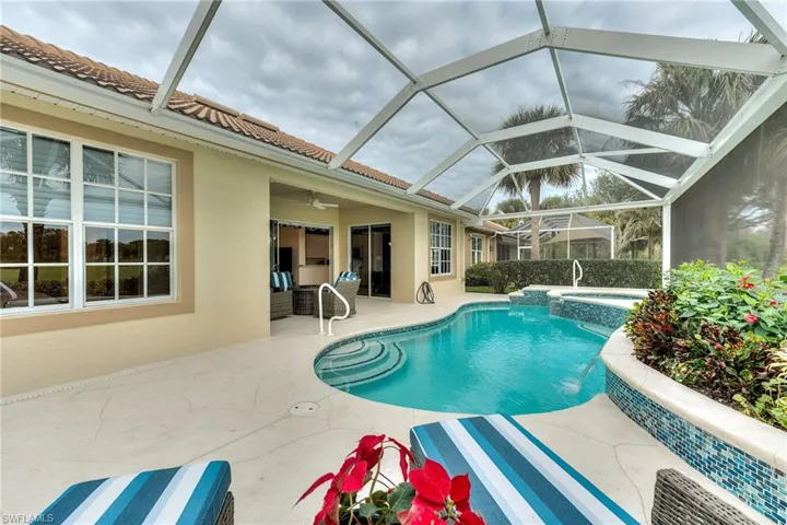 View of swimming pool with glass enclosure, ceiling fan, a patio area, pool water feature, and an in ground hot tub