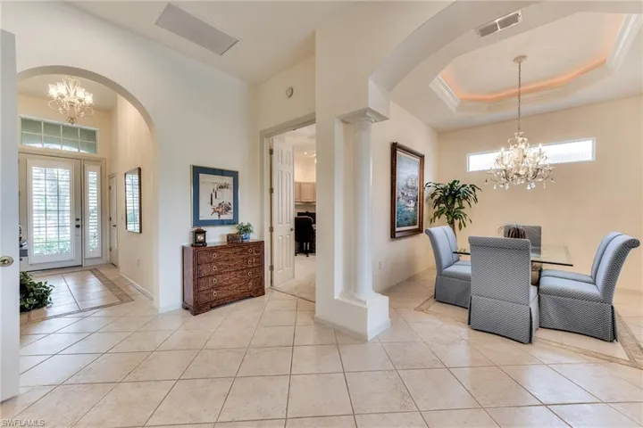 Dining space featuring an inviting chandelier, light tile patterned floors, plenty of natural light, and decorative columns