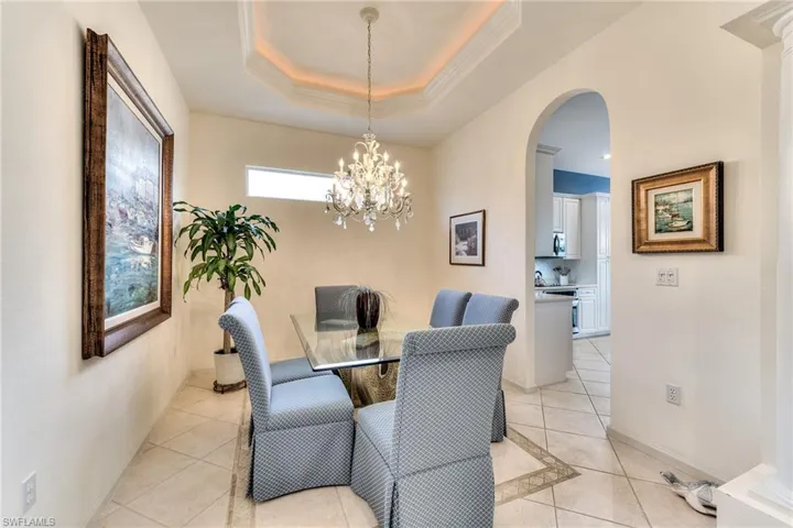 Dining area featuring crown molding, light tile patterned floors, a notable chandelier, and a tray ceiling