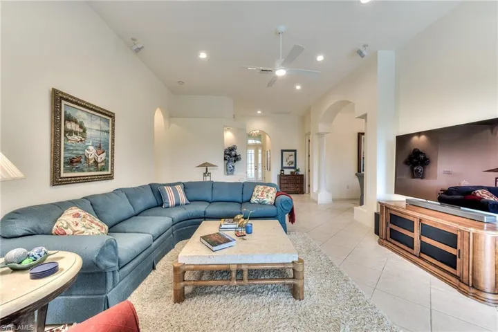 Living room featuring ceiling fan, light tile patterned floors, and ornate columns