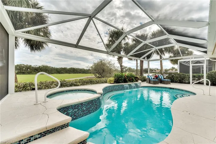 View of swimming pool with an in ground hot tub, a lanai, pool water feature, and a patio area