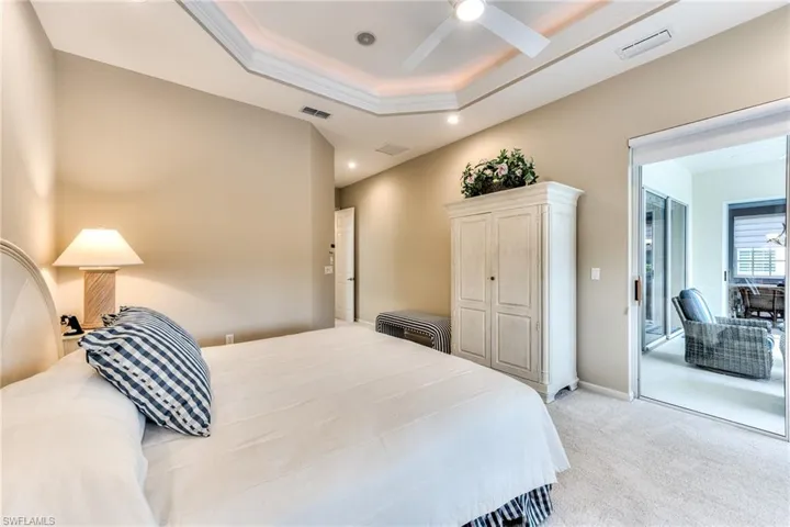 Bedroom featuring ceiling fan, light colored carpet, and a tray ceiling