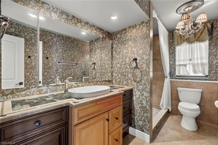 Bathroom featuring tile patterned floors, vanity, tile walls, toilet, and walk in shower