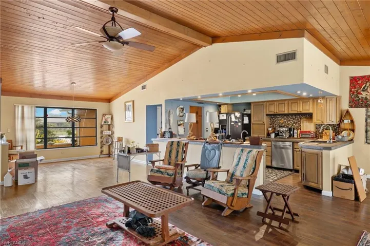 Living room featuring ceiling fan, sink, wooden ceiling, hardwood / wood-style flooring, and beamed ceiling