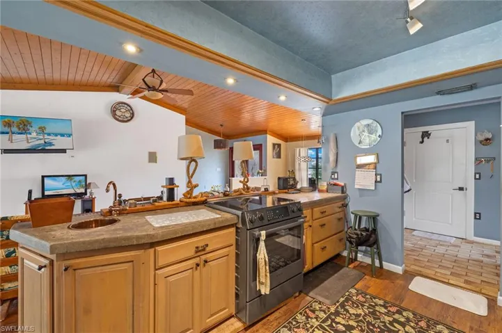Kitchen featuring ceiling fan, vaulted ceiling, stainless steel electric range, wooden ceiling, and sink