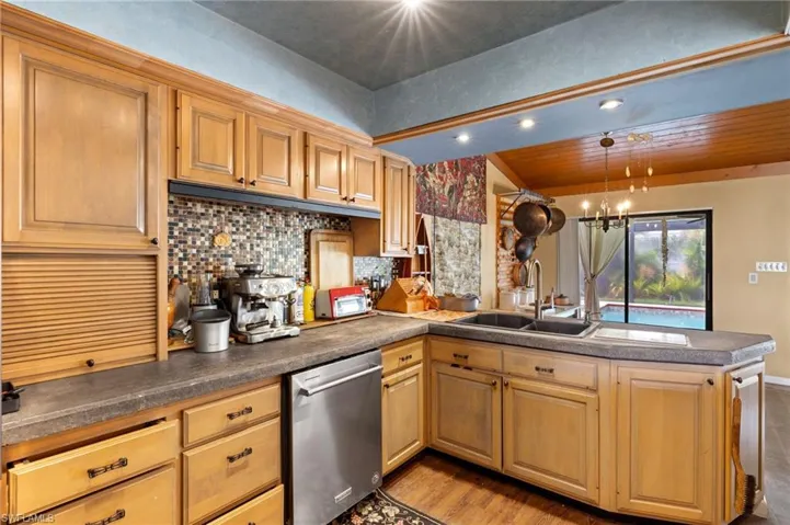 Kitchen featuring backsplash, light hardwood / wood-style floors, stainless steel dishwasher, sink, and kitchen peninsula