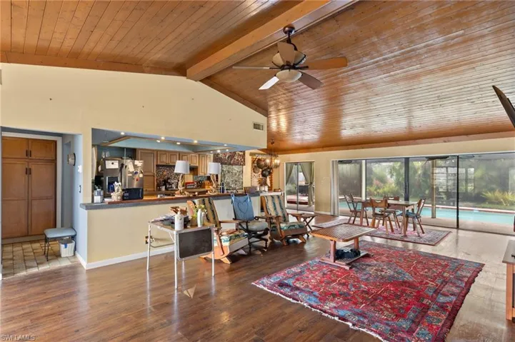 Living room with beam ceiling, hardwood / wood-style floors, high vaulted ceiling, wood ceiling, and ceiling fan